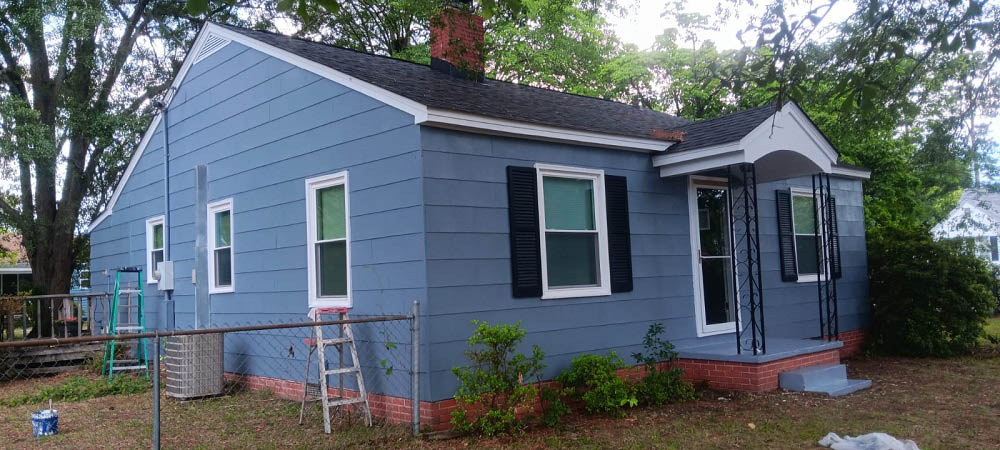 Home repainted cleanly in slate gray, with white trim and black shutters